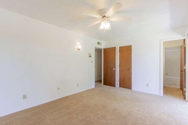 unfurnished bedroom with carpet, ceiling fan, and ensuite bath