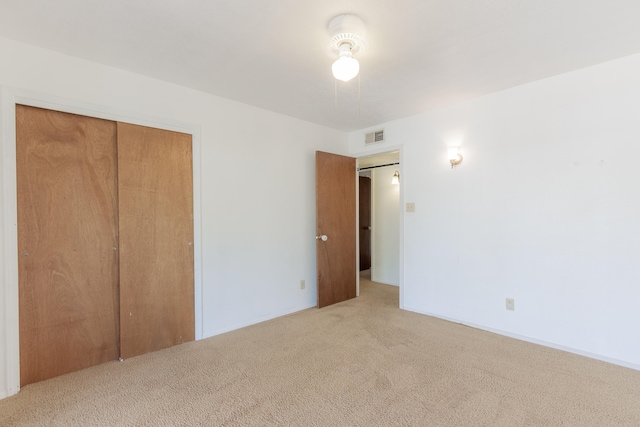 unfurnished bedroom with light carpet and a closet