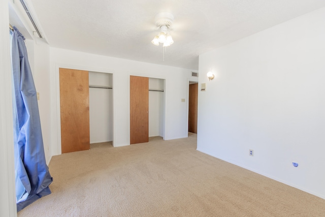 unfurnished bedroom with light carpet and multiple closets