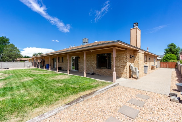 rear view of house featuring a lawn and a patio