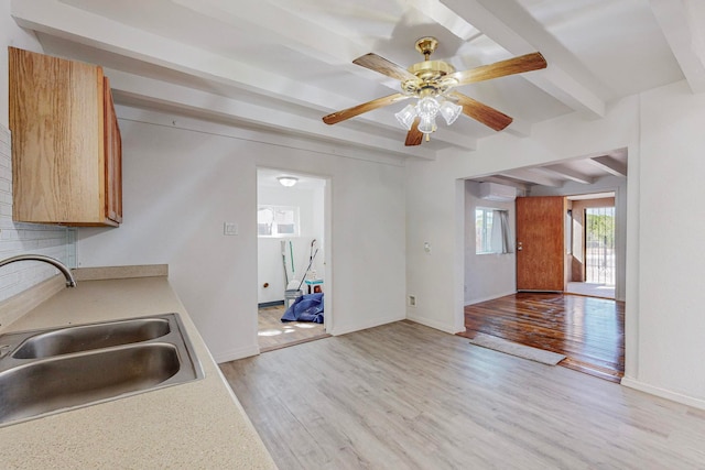 kitchen featuring beamed ceiling, ceiling fan, light hardwood / wood-style floors, and sink