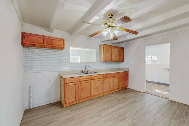 kitchen with decorative backsplash, beam ceiling, light wood-type flooring, and sink