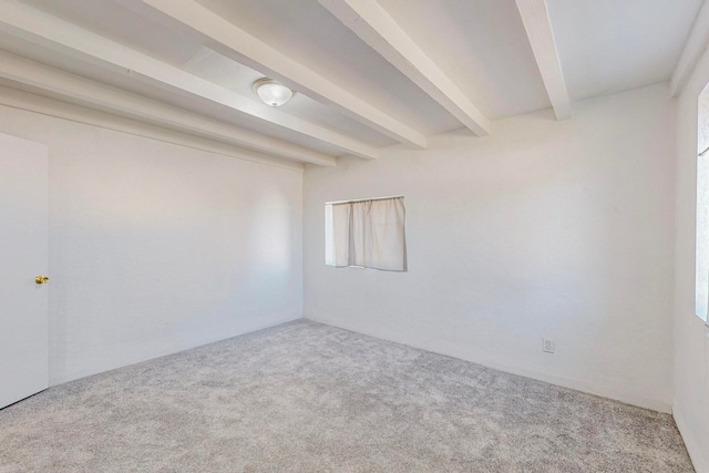 carpeted empty room with beamed ceiling