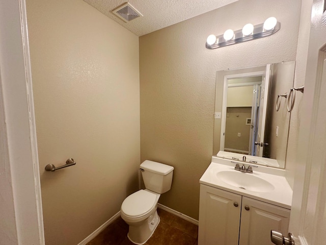 bathroom with a textured ceiling, vanity, and toilet