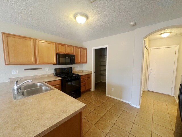 kitchen with black appliances, a textured ceiling, light tile patterned floors, and sink