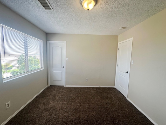 carpeted empty room featuring a textured ceiling