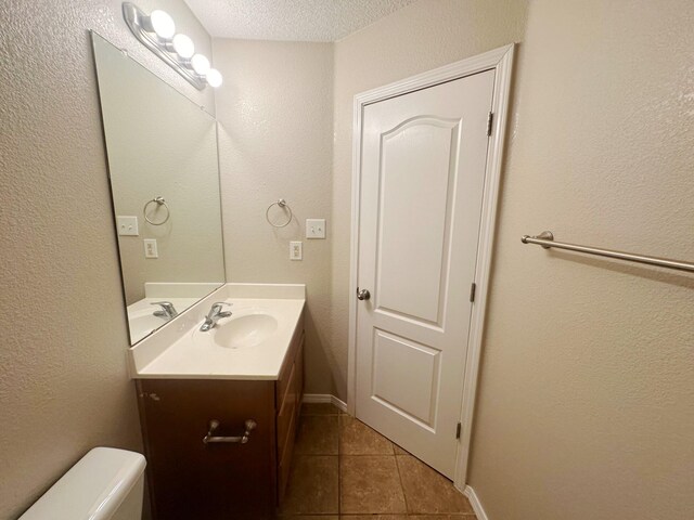 bathroom featuring a textured ceiling, vanity, toilet, and tile patterned floors