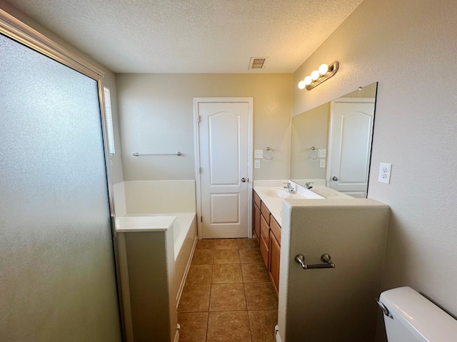 bathroom featuring a textured ceiling, vanity, a tub, tile patterned flooring, and toilet