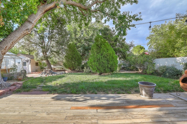 wooden terrace featuring fence and a yard