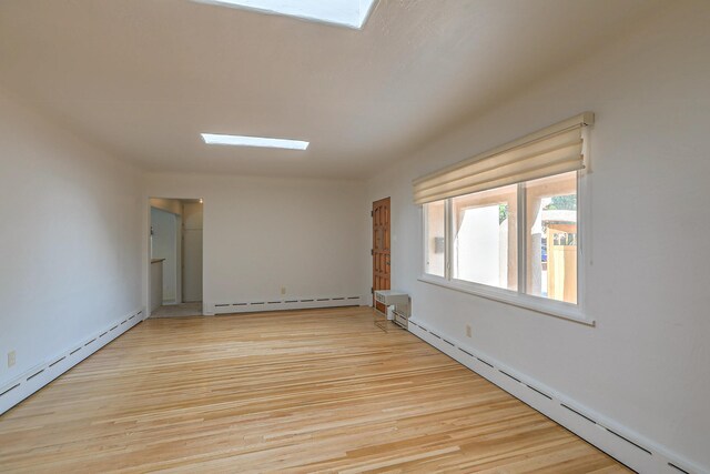 unfurnished room with baseboard heating and light wood-type flooring