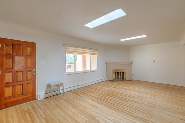 unfurnished living room featuring a baseboard radiator, a fireplace, light wood-style flooring, and a skylight