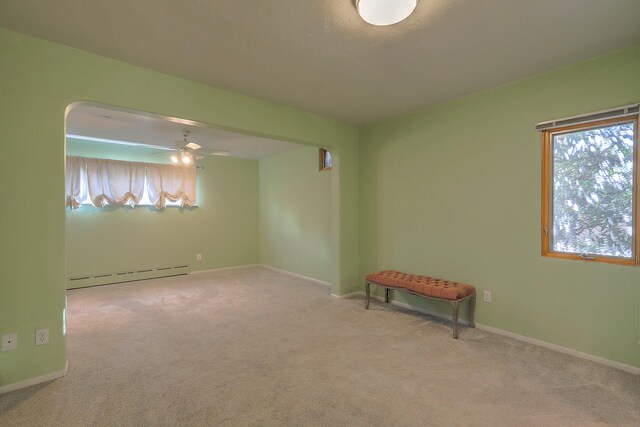 carpeted empty room with ceiling fan and baseboard heating