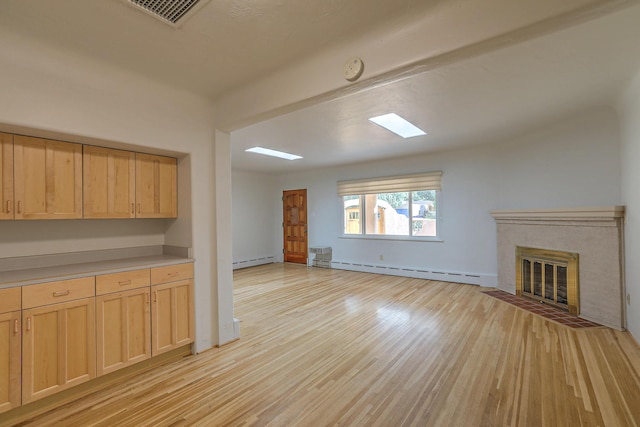 unfurnished living room featuring light wood-type flooring, a tile fireplace, visible vents, and baseboard heating