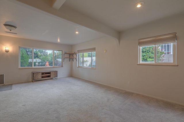 spare room featuring light colored carpet, beamed ceiling, visible vents, and baseboards