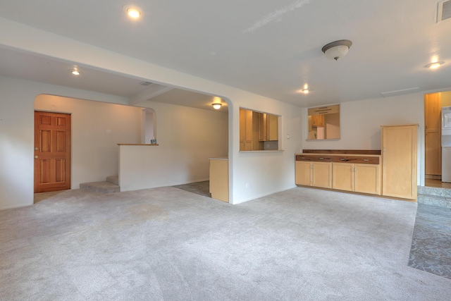 unfurnished living room featuring stairway, visible vents, arched walkways, and light colored carpet