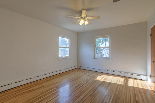 spare room featuring a baseboard heating unit, light wood-type flooring, visible vents, and a ceiling fan