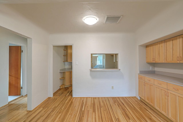 kitchen featuring light wood-type flooring, visible vents, light countertops, and light brown cabinetry