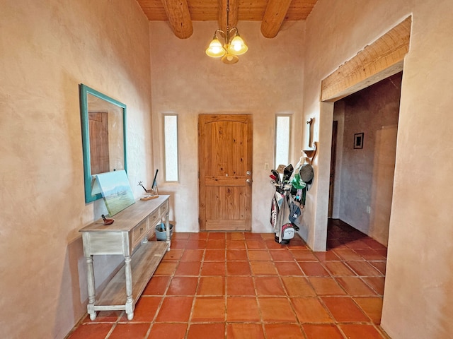 entrance foyer featuring tile patterned flooring, an inviting chandelier, beamed ceiling, and wooden ceiling