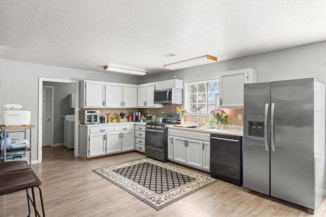 kitchen featuring tasteful backsplash, visible vents, a sink, light countertops, and stainless steel appliances