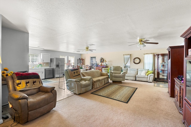 carpeted living room with ceiling fan, sink, and a textured ceiling