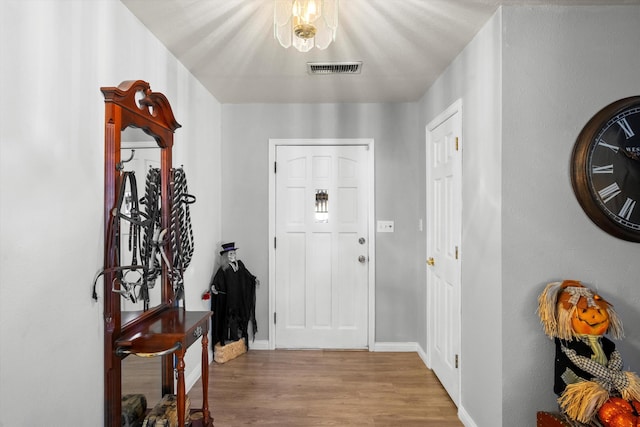 foyer featuring wood finished floors, baseboards, and visible vents