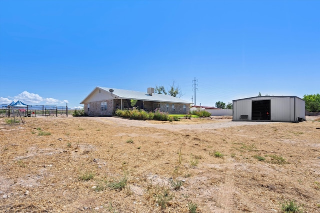view of yard with a garage, dirt driveway, fence, an outdoor structure, and an outbuilding
