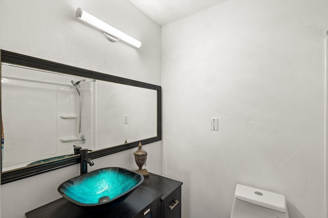 bathroom featuring a shower, vanity, and toilet