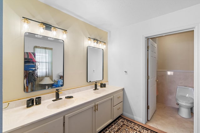 bathroom featuring tile patterned floors, double vanity, a sink, and toilet