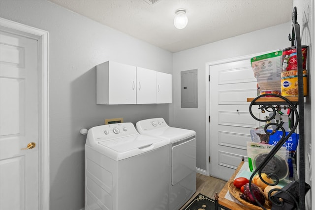 washroom featuring electric panel, a textured ceiling, light wood-style floors, independent washer and dryer, and cabinet space