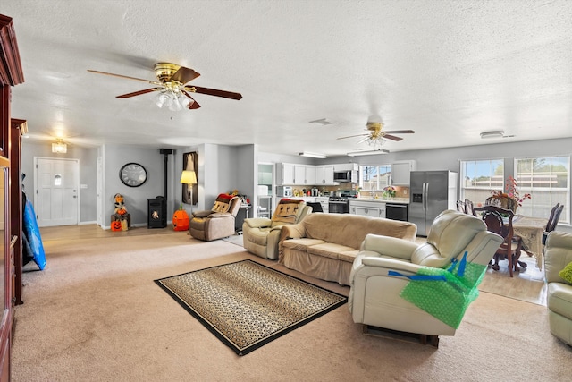 carpeted living room with ceiling fan and a textured ceiling