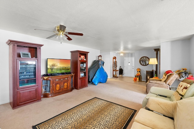 living room with light carpet, ceiling fan, and a textured ceiling