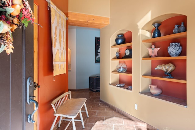 hallway with built in shelves and tile patterned floors