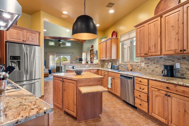 kitchen with butcher block counters, decorative light fixtures, a kitchen island, ceiling fan, and appliances with stainless steel finishes