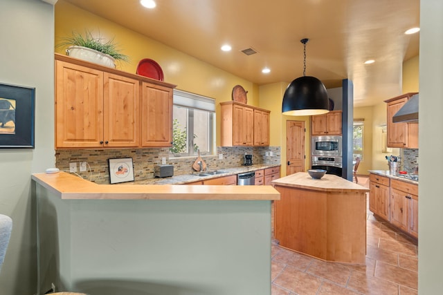 kitchen with backsplash, stainless steel appliances, sink, kitchen peninsula, and a kitchen island