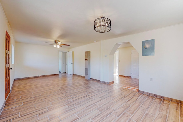 spare room with electric panel, ceiling fan with notable chandelier, and light wood-type flooring