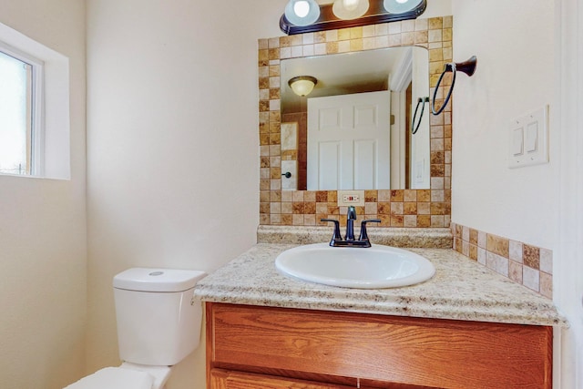 bathroom with vanity, toilet, and backsplash