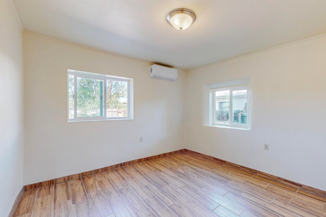 empty room featuring light wood-type flooring, ornamental molding, and a wall mounted air conditioner