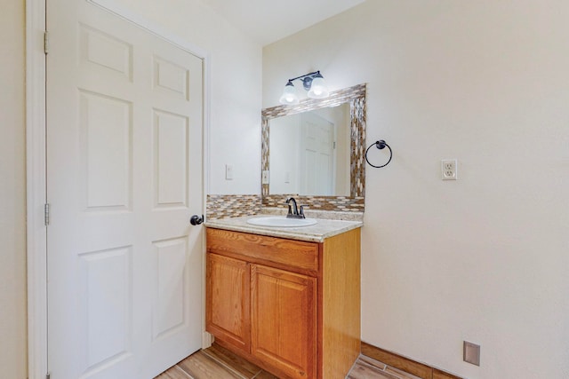 bathroom featuring wood-type flooring, decorative backsplash, and vanity