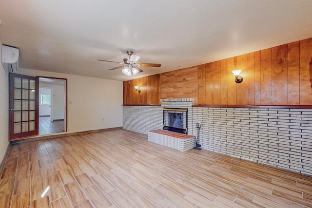 unfurnished living room with a fireplace, brick wall, ceiling fan, and light hardwood / wood-style floors