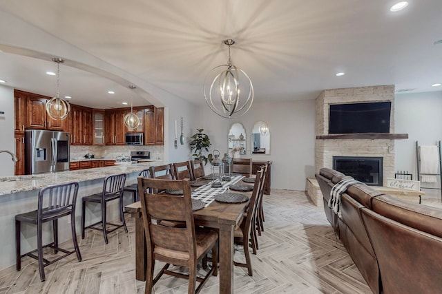 dining area with a fireplace, light parquet floors, a chandelier, and sink