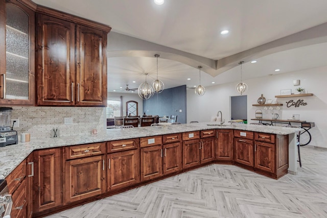 kitchen with pendant lighting, a notable chandelier, kitchen peninsula, sink, and light parquet flooring