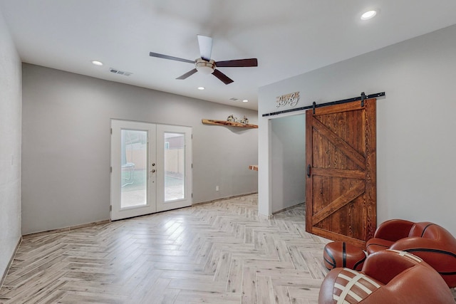 interior space with light parquet flooring, ceiling fan, and a barn door