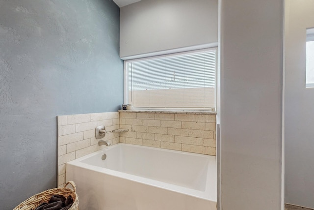 full bathroom featuring a bath and a textured wall