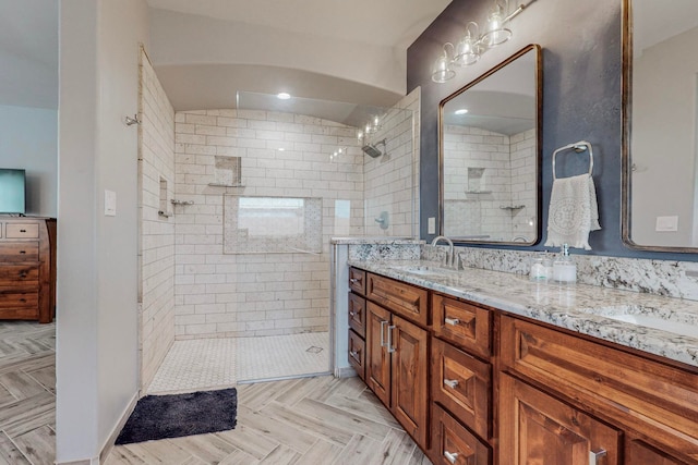 bathroom featuring parquet floors, vanity, and a tile shower