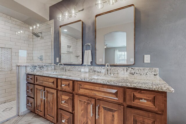bathroom featuring double vanity, tiled shower, ceiling fan, and a sink
