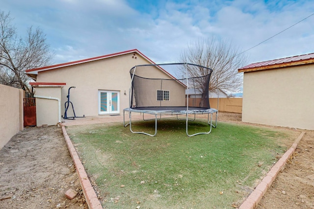 back of property with a lawn, a patio area, and a trampoline