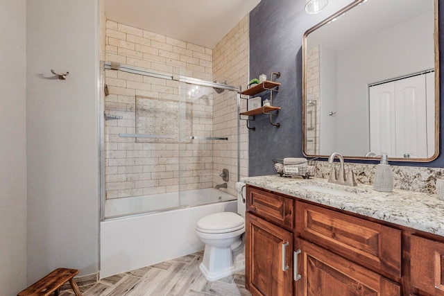 full bathroom featuring vanity, toilet, and bath / shower combo with glass door