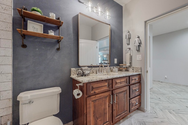 bathroom with toilet, parquet flooring, and vanity