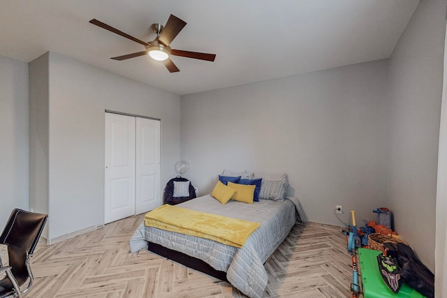 bedroom featuring light parquet flooring, ceiling fan, and a closet