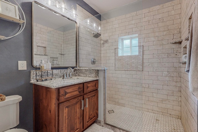 bathroom featuring toilet, a tile shower, and vanity